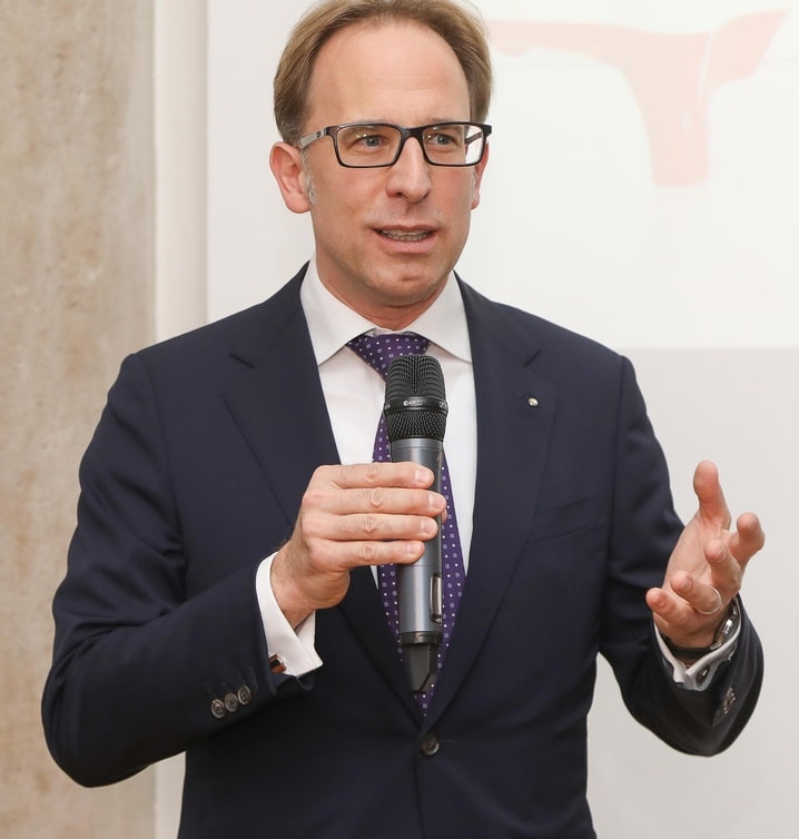 Foto von Peter Werth, CEO von Wolftank-Adisa. Werth trägt einen dunklen Anzug, trägt eine Brille und hat hellbraune Haare. Auf dem Foto hält er ein Mikrofon und spricht bei einem Event.